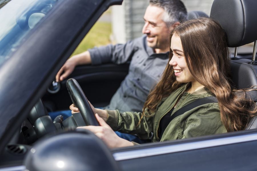 young woman behind the wheel of a car driving img